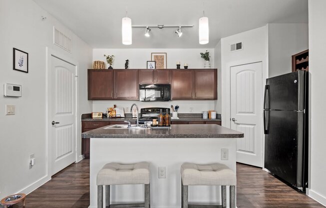 A kitchen with a black refrigerator and white walls.