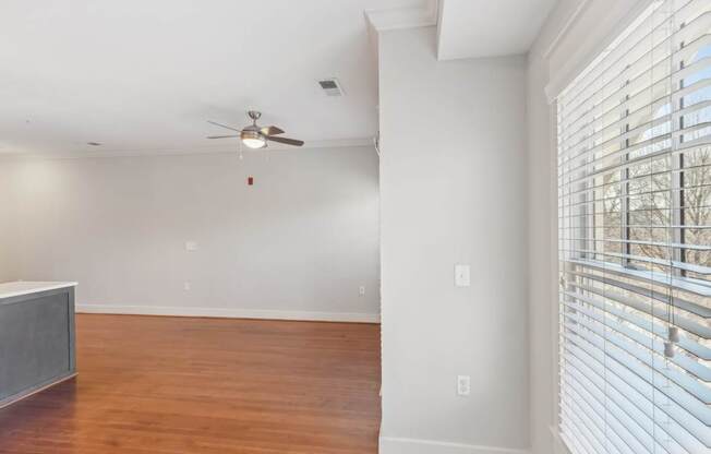 A room with a ceiling fan and a window with blinds.