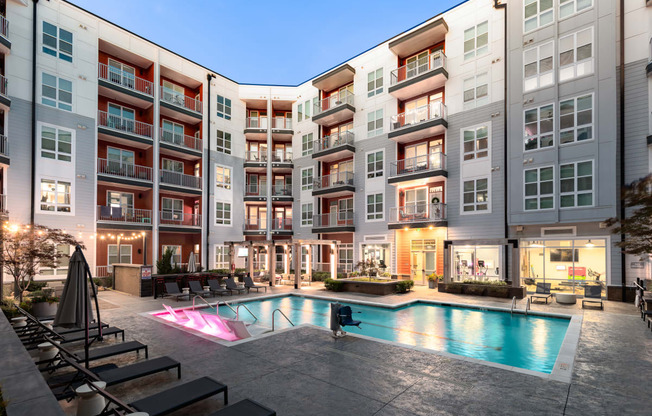 an apartment complex with a swimming pool and lounge chairs  at Abberly Noda Vista Apartment Homes, North Carolina, 28206