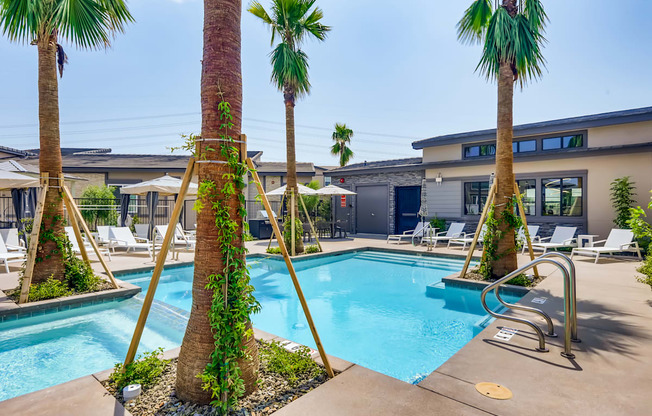 a swimming pool with palm trees and a building in the background at Grandstone at Sunrise, Peoria, Arizona