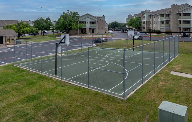 a tennis court in a city neighbourhood with apartments in the background