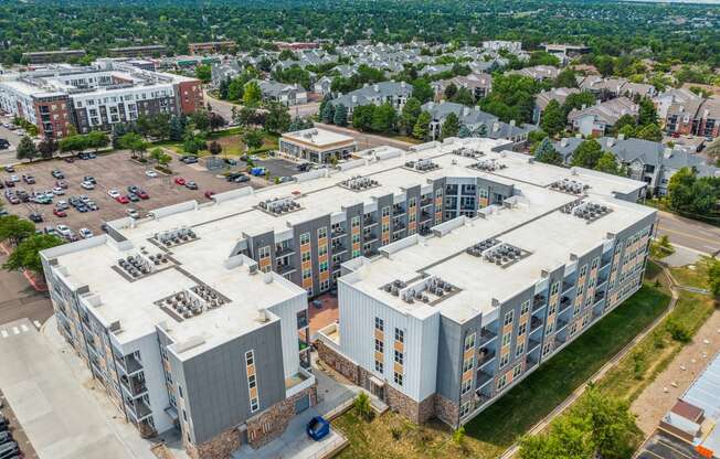 an aerial view of a large apartment building with a parking lot and a city in the background