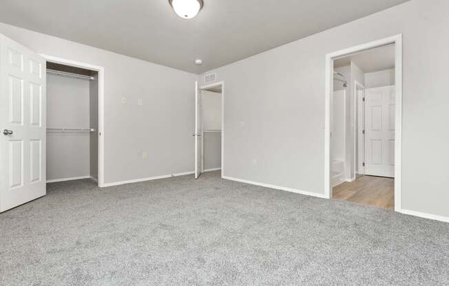 A spacious room with white walls and carpeted floor.