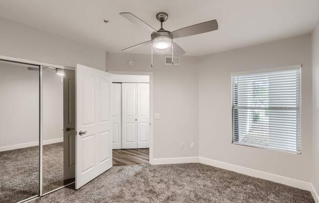 a bedroom with a ceiling fan and mirror