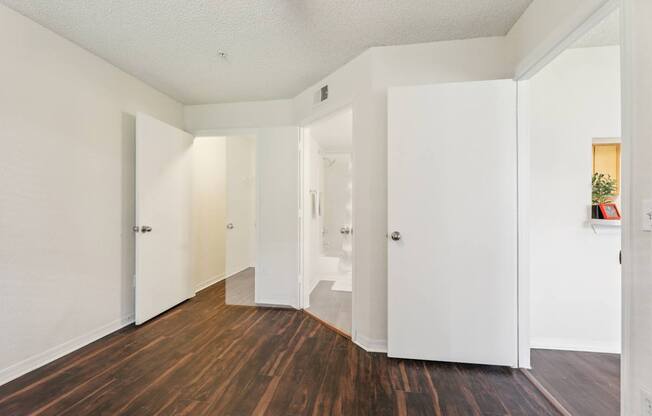 A hallway with white walls and wood floors.