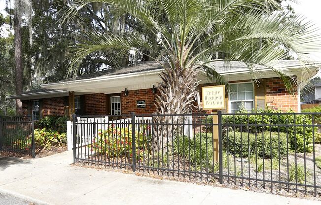 a house with a fence and a palm tree in front of it