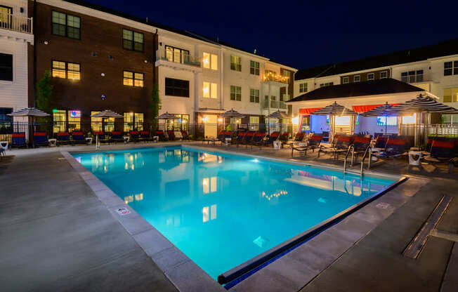 A large swimming pool in front of a building at night.