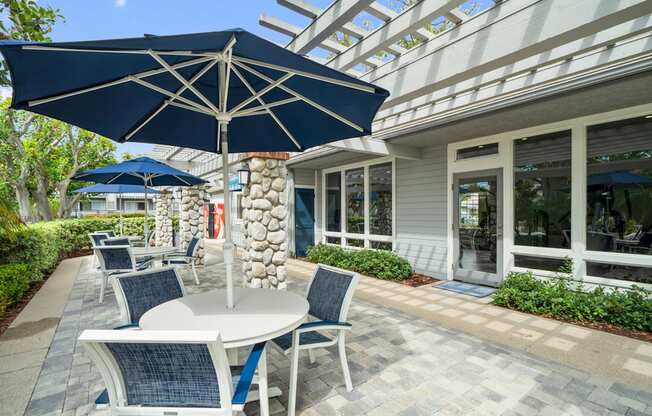 a patio with tables and umbrellas outside of a building