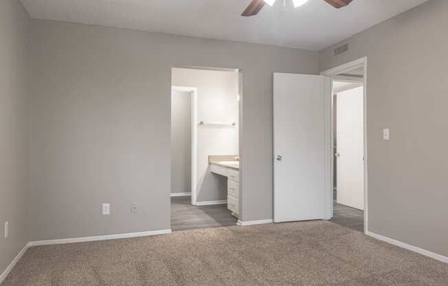 a bedroom with a desk and a ceiling fan