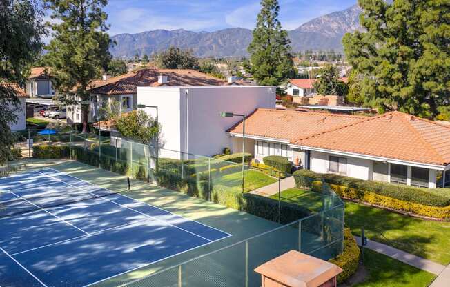 A tennis court surrounded by a fence and a building in the background.