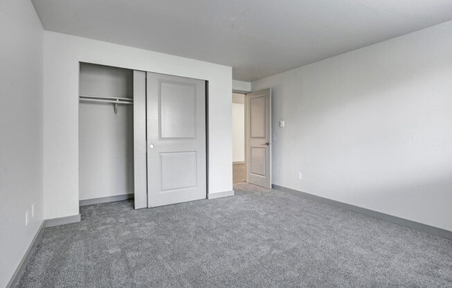 an empty bedroom with a closet and a door open