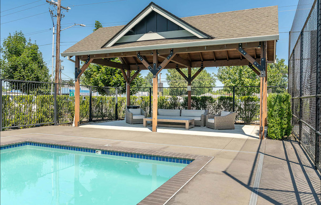 A pool with a brown roofed pavilion at Forestplace Apartment Homes, Forest Grove, OR, 97116