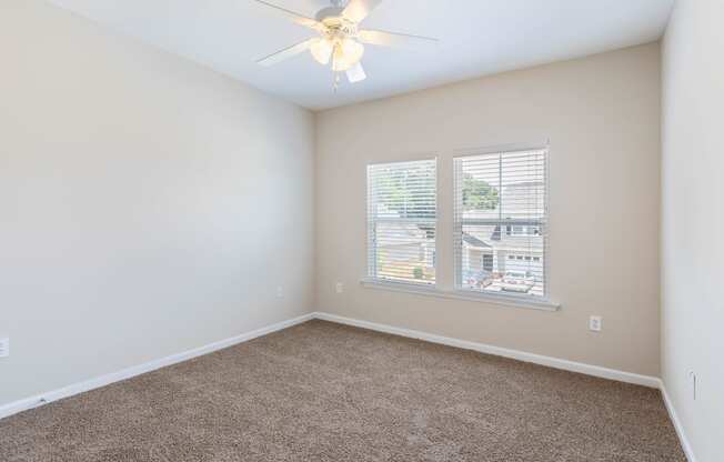 an empty bedroom with a ceiling fan and a window