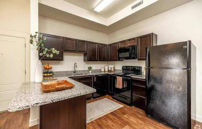 A kitchen with a black refrigerator and wooden cabinets.