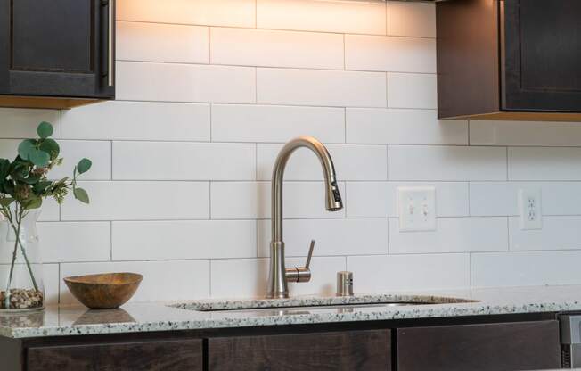 a kitchen with dark cabinets and white tile