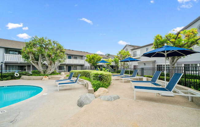 a pool with chairs and umbrellas in front of a building