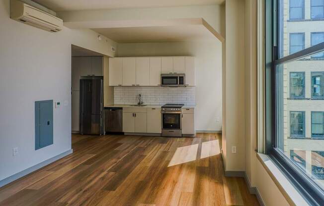 an empty living room with a large window and a kitchen at The Commonwealth Building, Pittsburgh, 15222