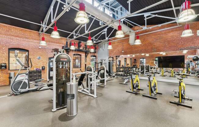 a gym with weights and cardio equipment and a brick wall at The Tannery, Glastonbury