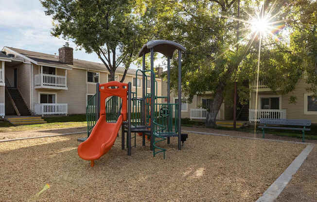 A playground with a red slide and a green swing set.