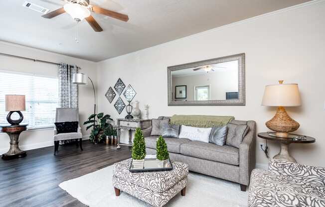 View of furnished living room with wood-designed flooring, ceiling fan and window at Riverstone apartments for rent in Macon, GA
