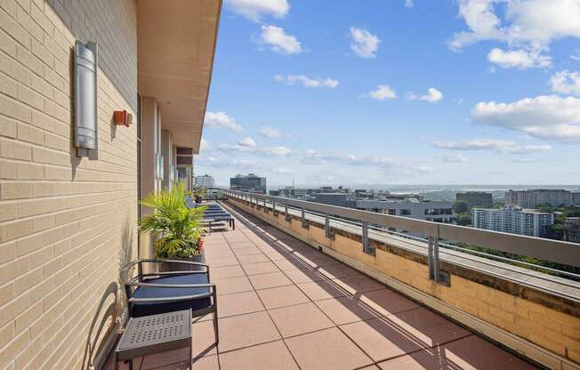 A balcony with a table and chairs overlooking a cityscape.