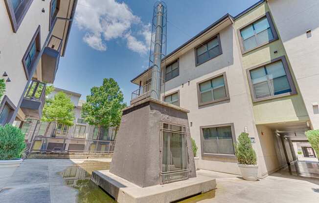 A small fountain in front of a building with a tall tower in the background. at Vue Live Oak, Dallas