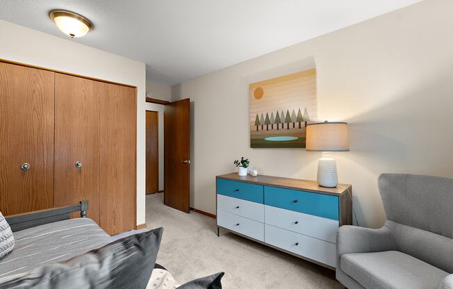 A living room with a grey couch, a wooden cabinet, and a painting on the wall.