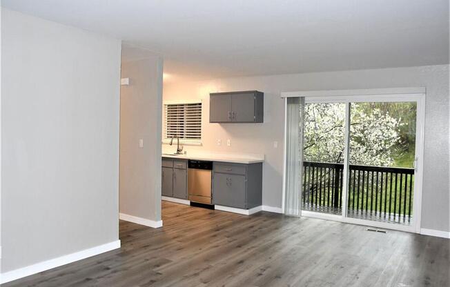 an empty living room with a sliding glass door to a balcony