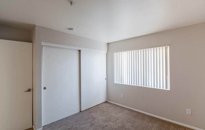 an empty bedroom with a closet and a window