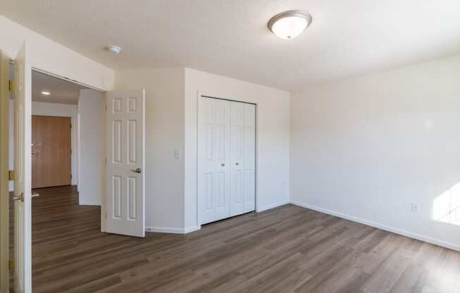 a bedroom with white walls and wood flooring. Fargo, ND Stonebridge Apartments