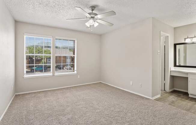 a bedroom with a large window and a ceiling fan