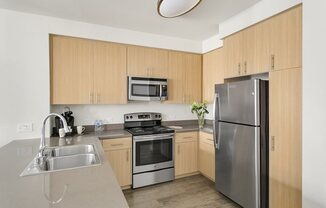 Redwood City, CA Apartments - mResidences Redwood City - Tan-Themed Kitchen with Light Tan Cabinetry, Silver Appliances, and Grey Granite Countertops