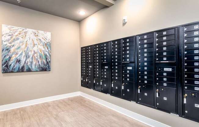 A row of black mailboxes are lined up on a wall.