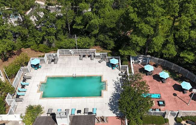 An aerial view of a pool surrounded by trees and lounge chairs.