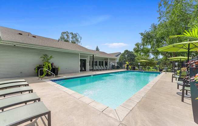 A pool surrounded by lounge chairs and umbrellas.
