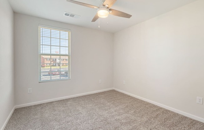 an empty room with a ceiling fan and a window