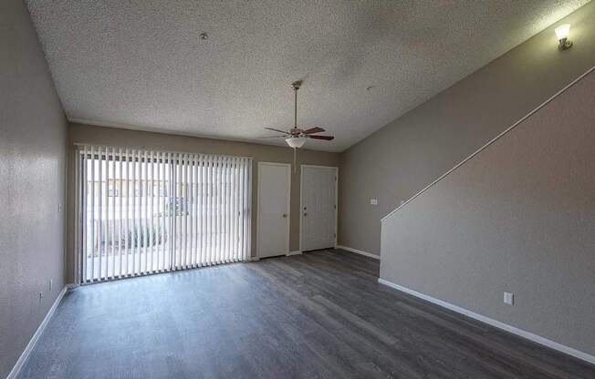 A room with a ceiling fan and sliding glass doors.