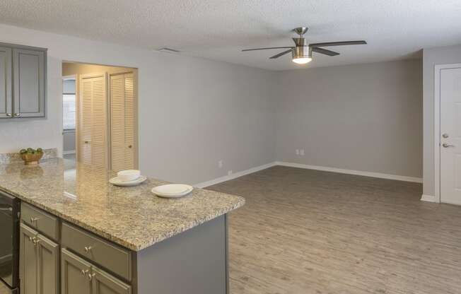 an empty kitchen and living room with a ceiling fan