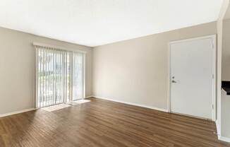 A room with wooden flooring and a sliding glass door.