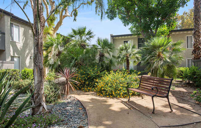 A bench sits in the middle of a garden at Twenty 2 Eleven Apartment Homes