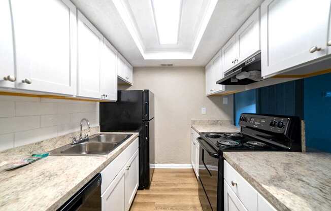 A kitchen with black appliances and white cabinets.