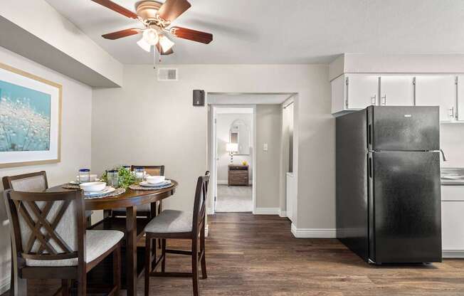 A black refrigerator is in a kitchen with a dining table and chairs.