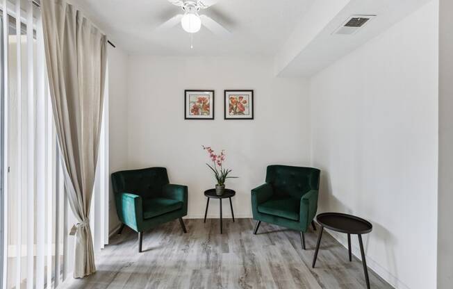 a living room with two green chairs and a ceiling fan