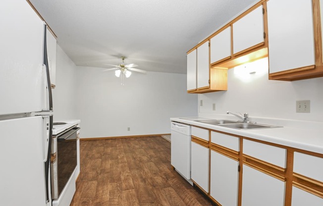 a kitchen with white cabinets and stainless steel appliances and a wood floor. Anoka, MN Dellwood Estates