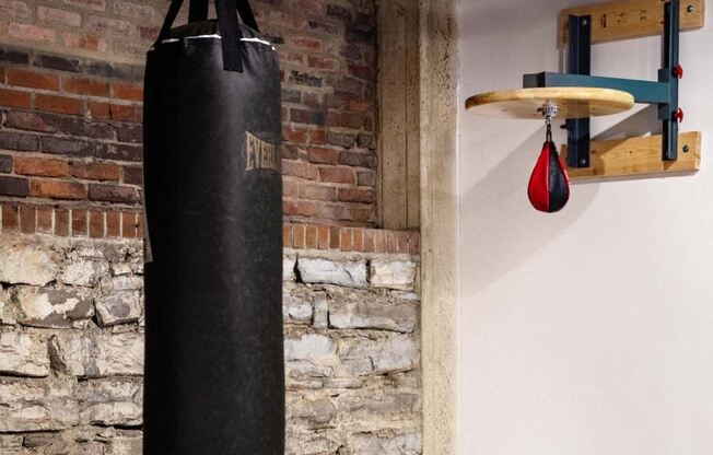 a punching bag hanging from a brick wall next to a punching ball on a rack