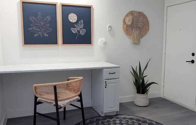 A room with a desk, chair, and two framed pictures on the wall.