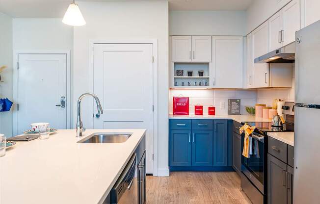 A kitchen with a white counter top and blue cabinets at the Mastlight.