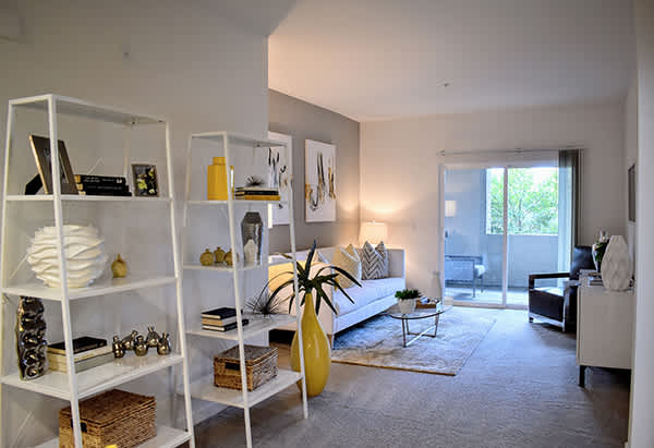 A living room with white shelves and a grey carpet.
