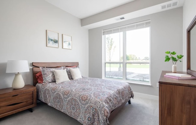 A bedroom with a bed, nightstand, and window.