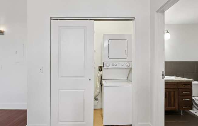 A white door is open to a room with a washer and dryer